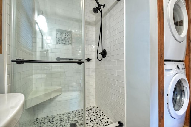 bathroom featuring stacked washer and dryer and an enclosed shower