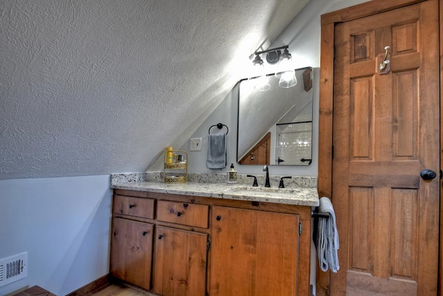 bathroom featuring lofted ceiling, a textured ceiling, and vanity