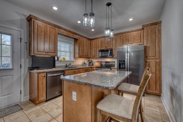 kitchen with appliances with stainless steel finishes, dark stone countertops, pendant lighting, a center island, and a breakfast bar