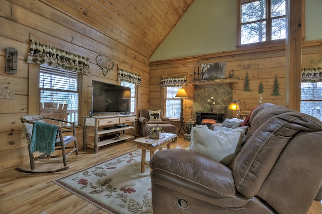 living room featuring high vaulted ceiling, wood walls, wood-type flooring, a fireplace, and wood ceiling