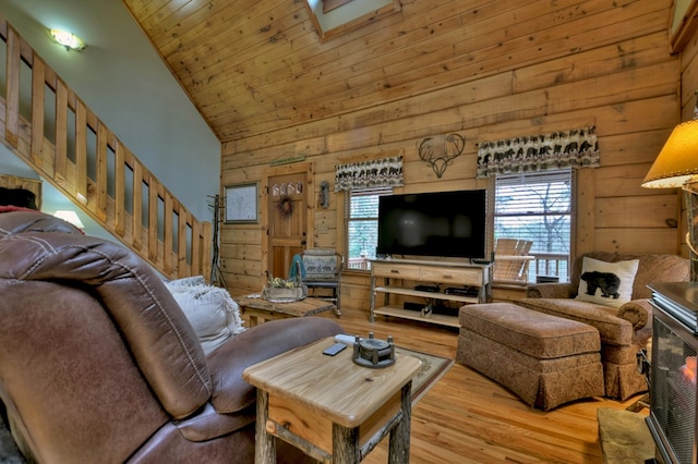 living room with wood walls, high vaulted ceiling, and light hardwood / wood-style floors