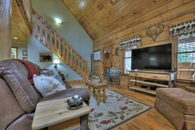 living room featuring light wood-type flooring, wooden ceiling, plenty of natural light, and wooden walls