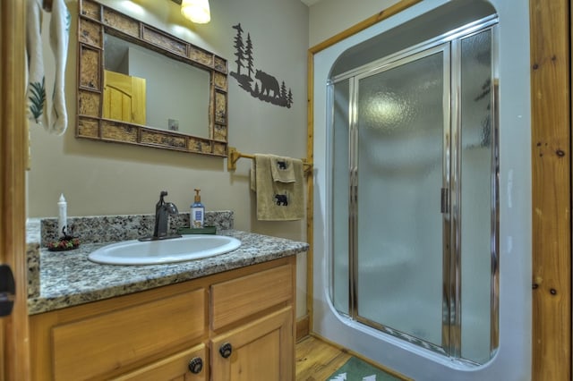 bathroom with vanity, wood-type flooring, and a shower with door