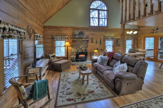 living room with a wood stove, high vaulted ceiling, an inviting chandelier, hardwood / wood-style flooring, and wood ceiling