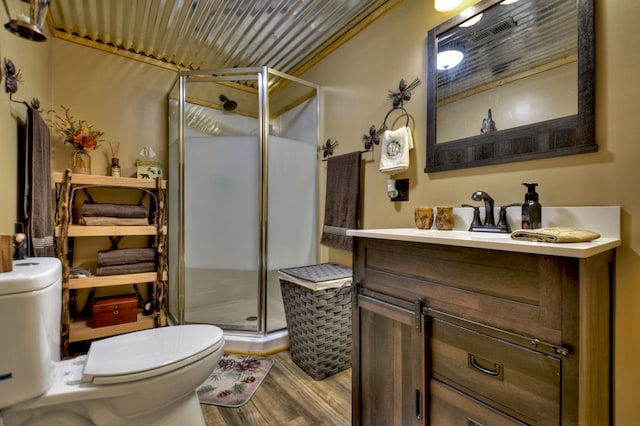 bathroom with a shower with door, vanity, wood-type flooring, and toilet