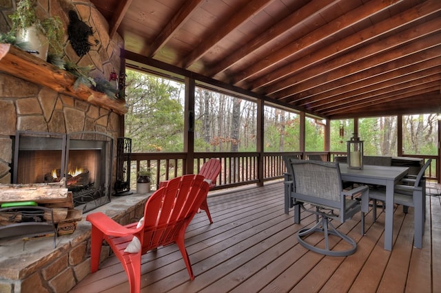 sunroom / solarium with vaulted ceiling with beams, an outdoor stone fireplace, and wooden ceiling