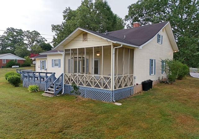 back of property with a yard and a sunroom