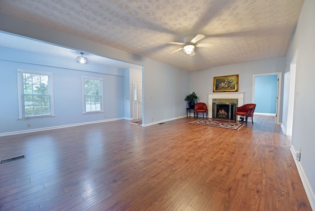 living room with ceiling fan, dark hardwood / wood-style floors, a textured ceiling, and a high end fireplace