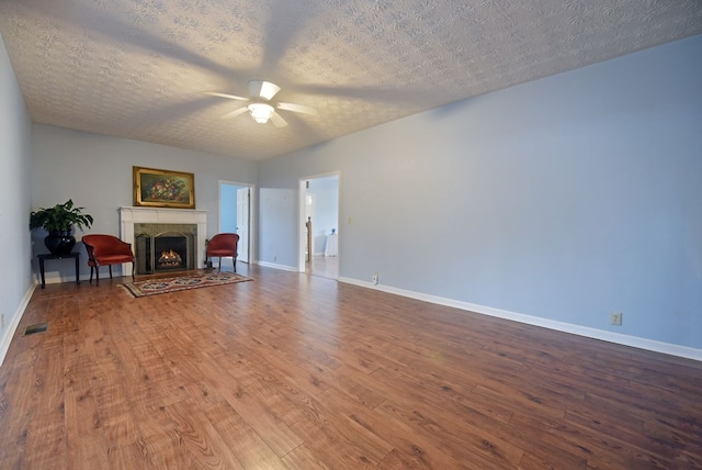 unfurnished living room featuring hardwood / wood-style flooring, ceiling fan, a fireplace, and a textured ceiling