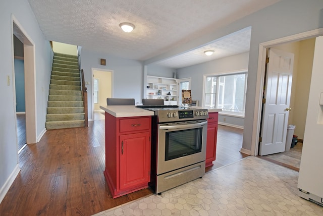 kitchen with a kitchen island, a textured ceiling, stainless steel gas range, and light hardwood / wood-style floors