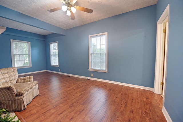 unfurnished room with ceiling fan, wood-type flooring, a textured ceiling, and plenty of natural light