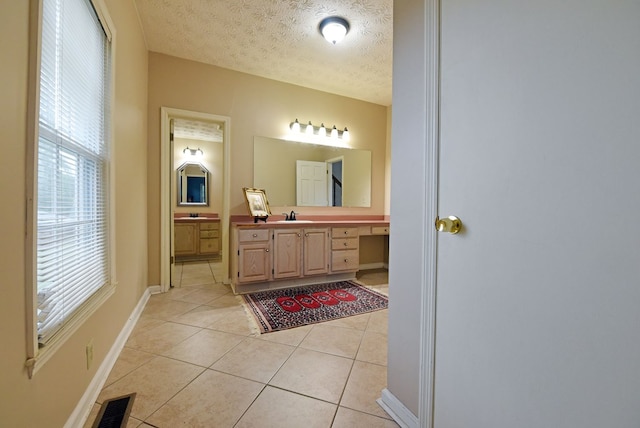 bathroom with tile patterned floors, vanity, a textured ceiling, and a wealth of natural light