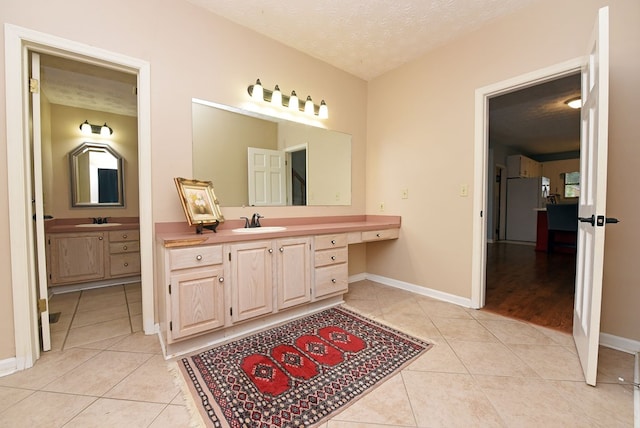 bathroom featuring tile patterned flooring, vanity, and a textured ceiling