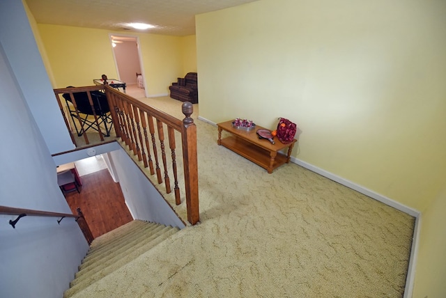 staircase featuring a textured ceiling and carpet flooring