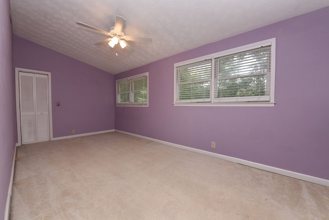 carpeted spare room with vaulted ceiling, ceiling fan, and a textured ceiling