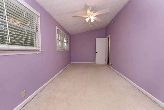 carpeted empty room with ceiling fan, lofted ceiling, and a textured ceiling