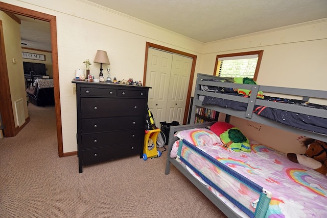 carpeted bedroom featuring a textured ceiling, a closet, and crown molding