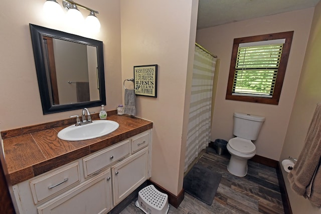 bathroom with vanity, hardwood / wood-style flooring, toilet, walk in shower, and a textured ceiling