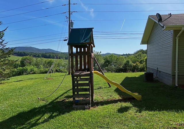 view of playground with a mountain view, a yard, and cooling unit