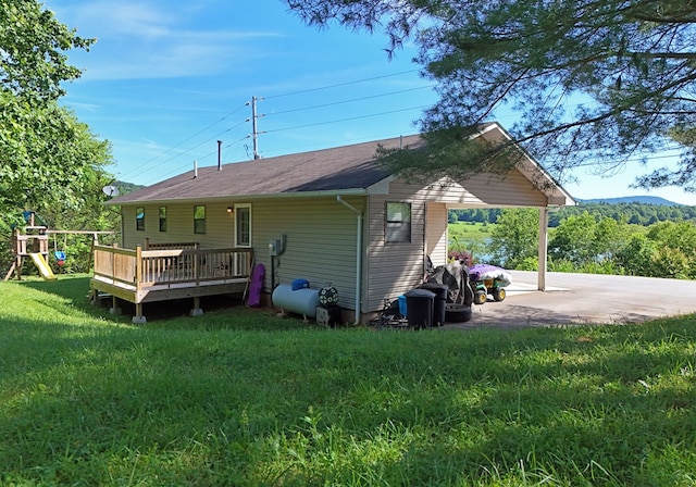 rear view of house featuring a lawn, a patio area, a playground, and a deck