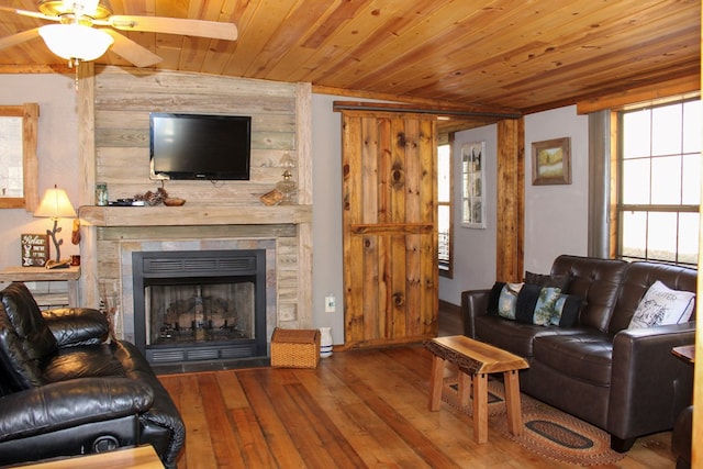 living room with a stone fireplace, ceiling fan, wooden ceiling, and hardwood / wood-style flooring