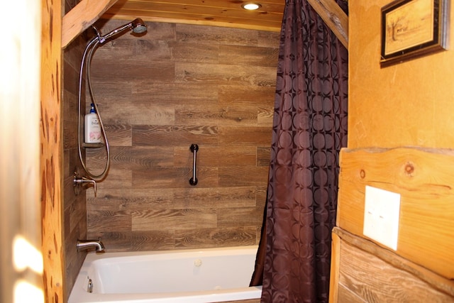 bathroom with wooden walls and shower / tub combo