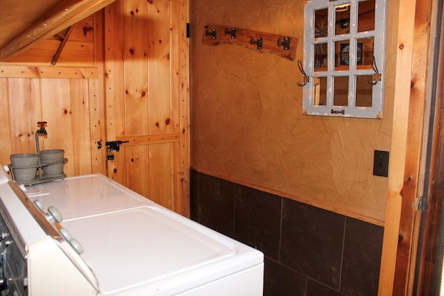 laundry area featuring wooden walls and independent washer and dryer