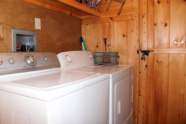 clothes washing area featuring separate washer and dryer and wooden walls