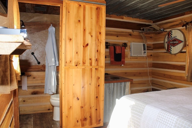 bedroom with a wall unit AC, ensuite bath, and wood walls