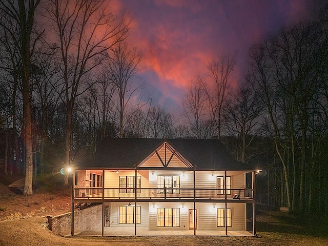 back house at dusk featuring a patio and a wooden deck