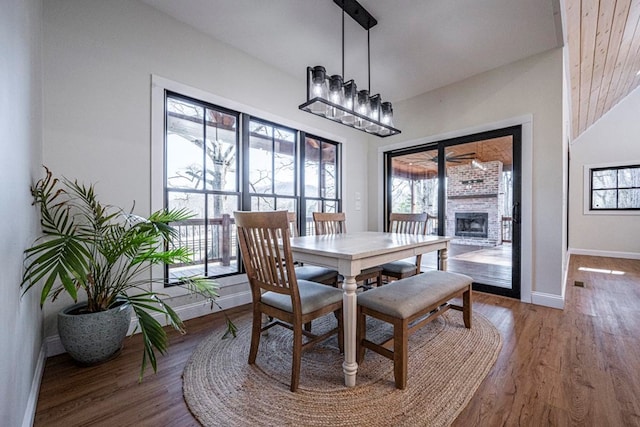 dining room featuring vaulted ceiling, hardwood / wood-style floors, and a fireplace