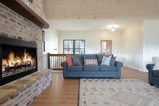 living room featuring beam ceiling, a brick fireplace, and light hardwood / wood-style flooring