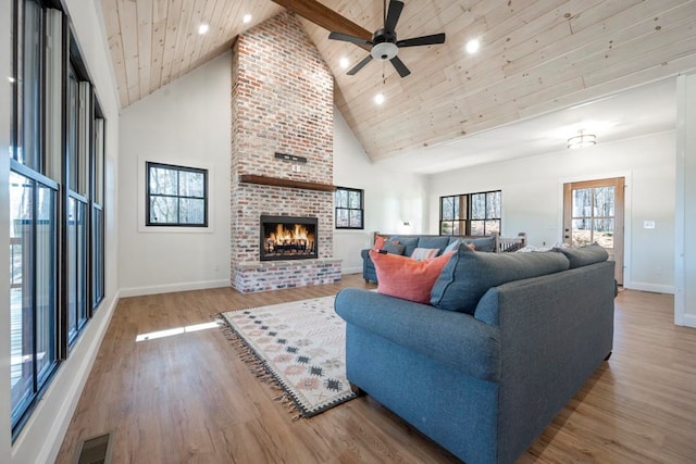 living room with high vaulted ceiling, ceiling fan, wood ceiling, a brick fireplace, and light wood-type flooring