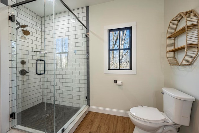 bathroom featuring hardwood / wood-style floors, a shower with door, and toilet