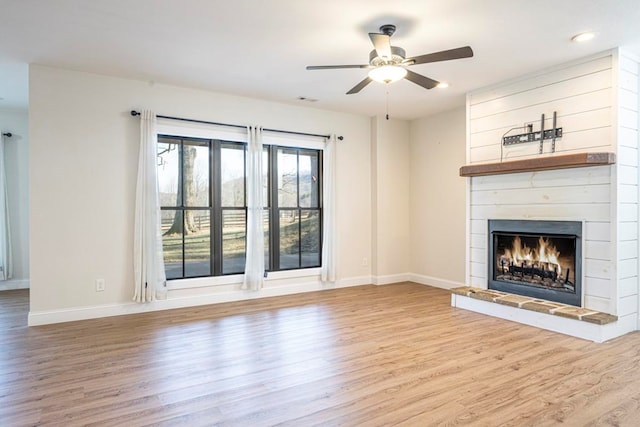 unfurnished living room with hardwood / wood-style flooring, ceiling fan, and a fireplace