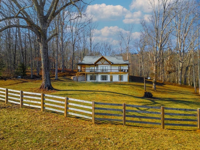 view of front of home with a deck, a front yard, and a rural view