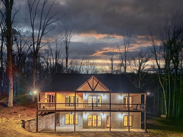 back house at dusk with a patio and a wooden deck