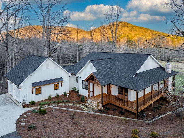 rear view of property featuring a mountain view, a garage, and covered porch