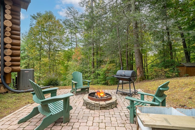 view of patio featuring a fire pit, a grill, a storage unit, and central air condition unit