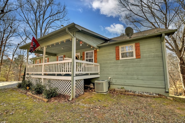 rear view of house with central AC unit, a yard, and a porch