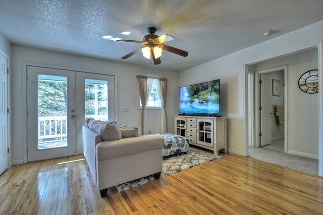 living room with ceiling fan, light hardwood / wood-style flooring, french doors, and a textured ceiling