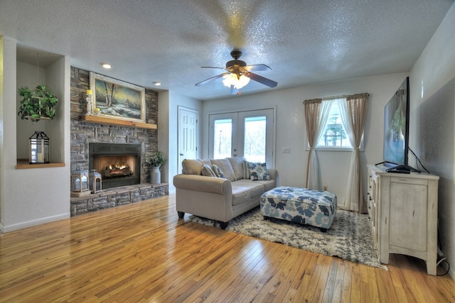 living room featuring hardwood / wood-style flooring, a fireplace, a textured ceiling, and french doors