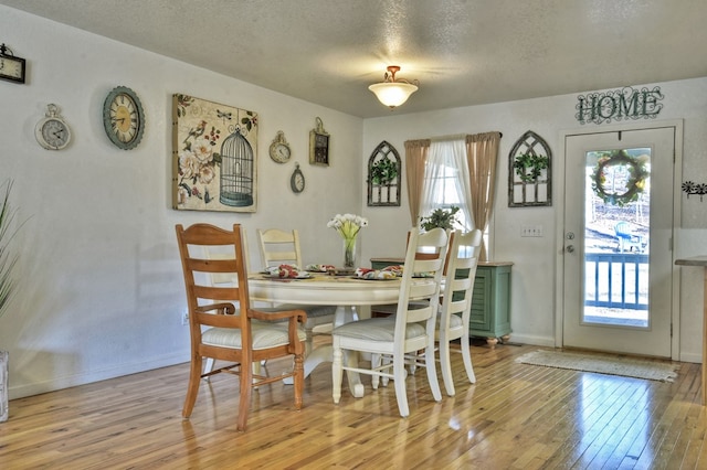 dining room featuring a healthy amount of sunlight, a textured ceiling, and light wood-type flooring