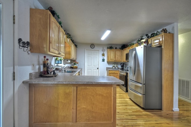 kitchen featuring sink, a textured ceiling, light wood-type flooring, kitchen peninsula, and stainless steel appliances