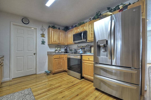 kitchen with appliances with stainless steel finishes and light hardwood / wood-style floors