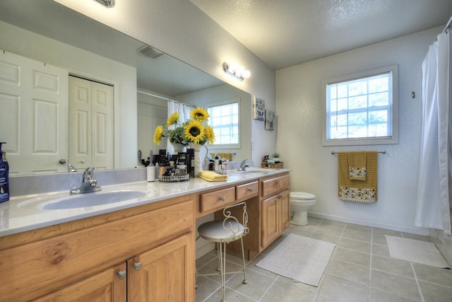 bathroom with vanity, plenty of natural light, tile patterned floors, and toilet