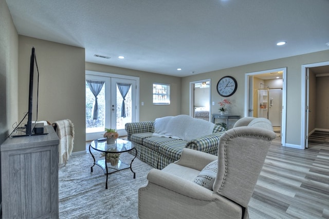 living room with light hardwood / wood-style floors, french doors, and a textured ceiling