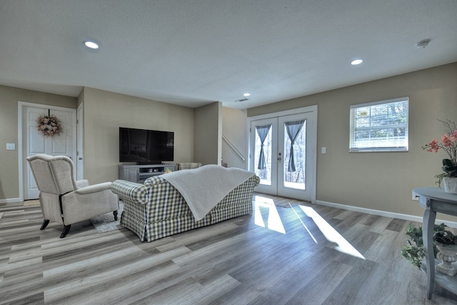 living room with french doors, a textured ceiling, and light wood-type flooring