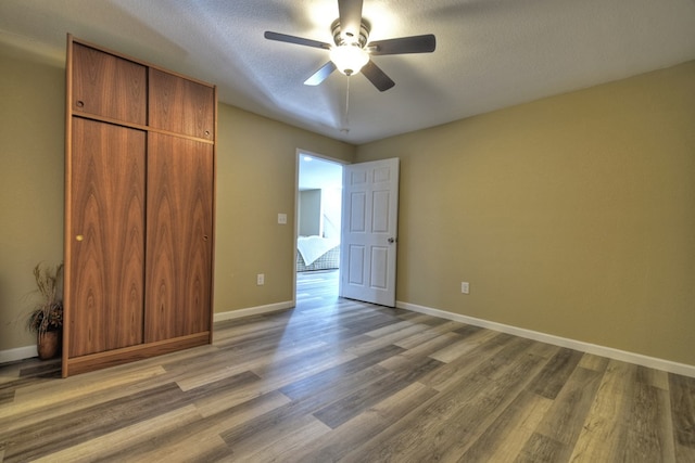 unfurnished bedroom with hardwood / wood-style flooring, ceiling fan, a closet, and a textured ceiling