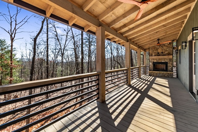 wooden deck with ceiling fan and an outdoor stone fireplace